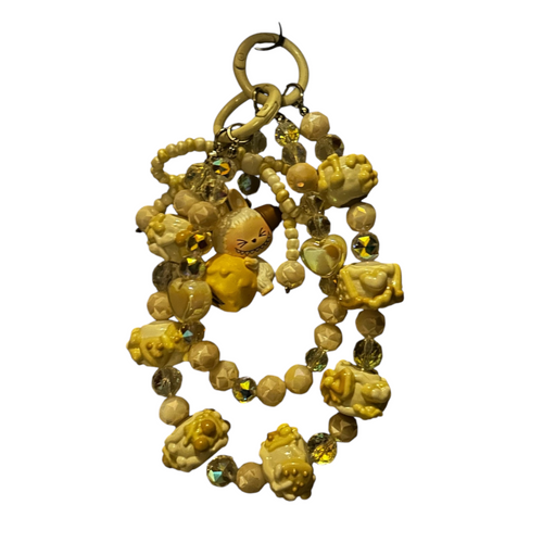 Cavalla Goods handcrafted beaded phone charm in yellow and cream with crystal accents, heart beads, and character charms.
